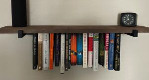 Photo of Hanging Bookshelf with a block and water bottle on top and 15 books hanging beneath the shelf