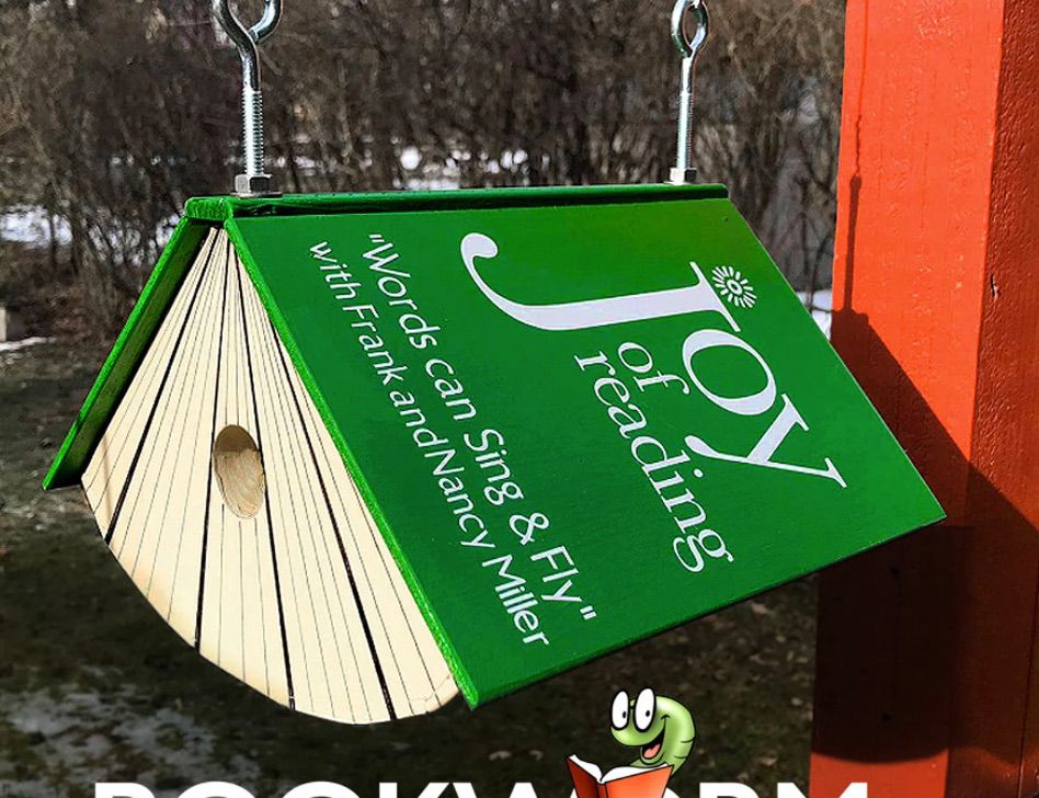 Image of a green birdhouse in the shape of a book. The book is titled "Joy of Reading."