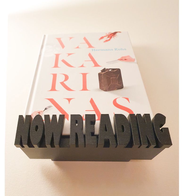 Image of a floating display shelf. It is black and says "now reading" with a book inside. 