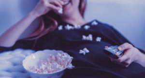 woman watching television and eating popcorn for film and tv
