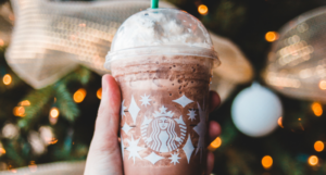 a photo of someone holding a starbucks cup up to a Christmas tree
